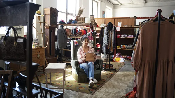 1769857009-woman-sitting-thrift-shop-full-shot