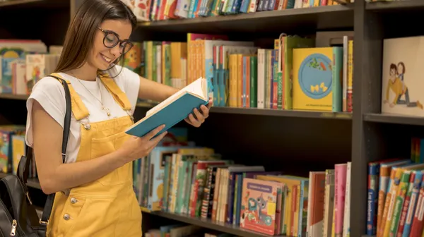 1763045053-teenage-student-reading-book-leaning-shelf