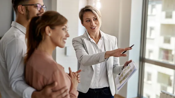 1768481878-smiling-real-estate-agent-talking-with-couple-interested-buying-new-home